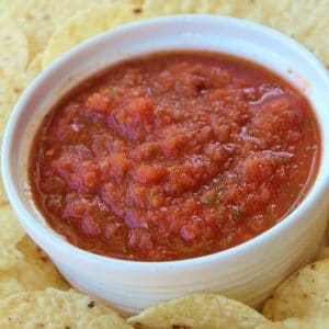 Bowl of restaurant style salsa with chips surrounding it