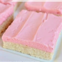 Up close photo of a plate of sugar cookie bars with pink frosting.