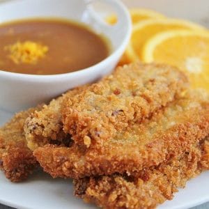 Stack of Beef Strips with a bowl of Orange Dijon Dipping sauce and orange slices in the background.