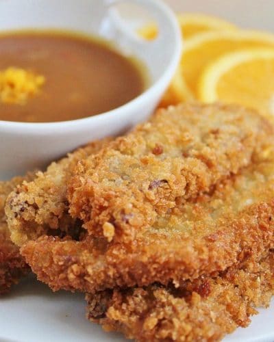 Stack of Beef Strips with a bowl of Orange Dijon Dipping sauce and orange slices in the background.