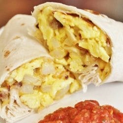 Breakfast Burrito cut in half on a plate with salsa.