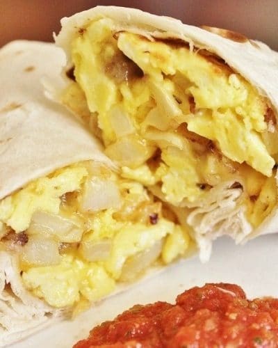 Breakfast Burrito cut in half on a plate with salsa.