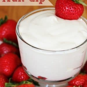 Bowl of fruit dip surrounded by whole strawberries.