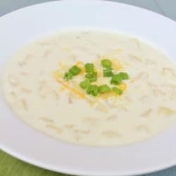 Bowl of Creamy Potato Soup, topped with green onions and cheddar cheese.