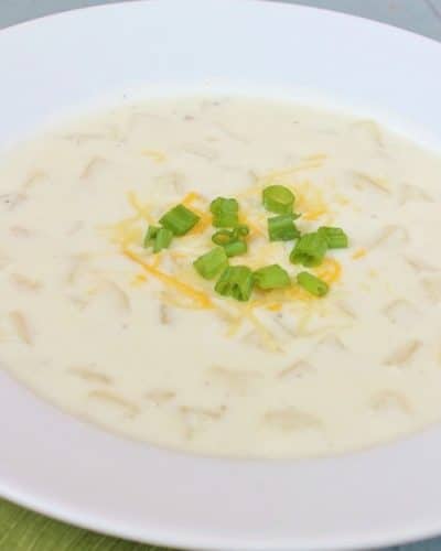 Bowl of Creamy Potato Soup, topped with green onions and cheddar cheese.
