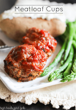Two meatloaf cups with ketchup on top and asparagus on the side.