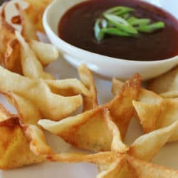 Plate of Cream Cheese Rangoons with a bowl of dipping sauce