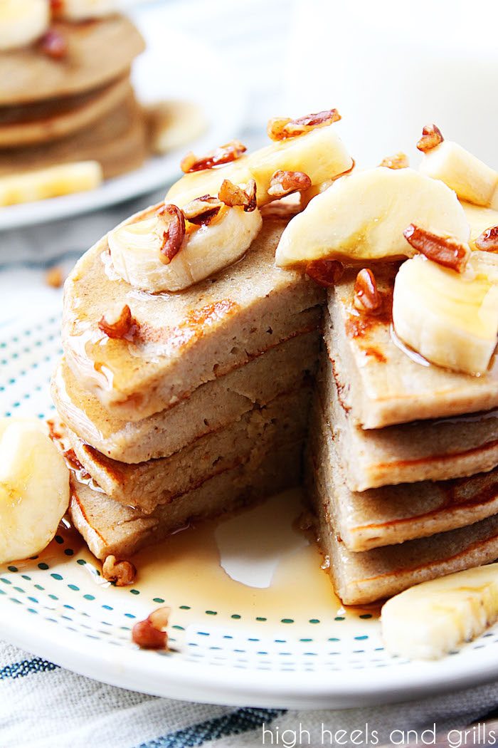 Healthy Banana Pancakes - Bite taken out of stack with bananas and pecans on top.