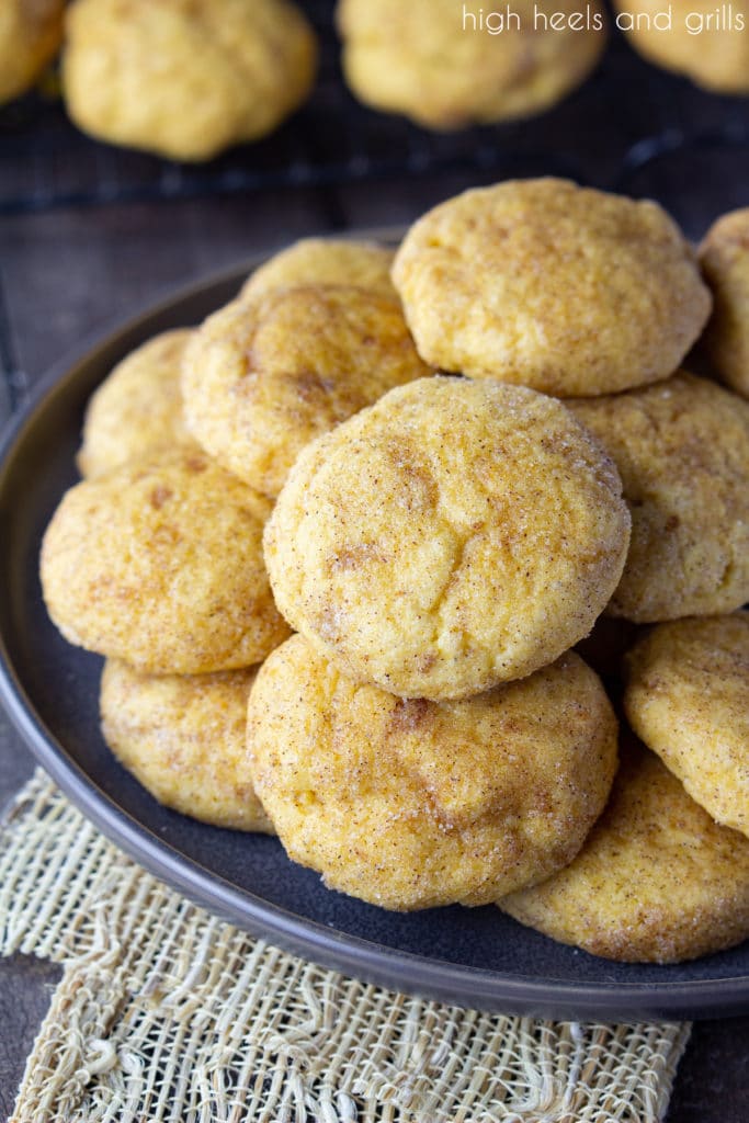 Plate of Pumpkin Snickerdoodles with a cooling rack of cookies in the back. 