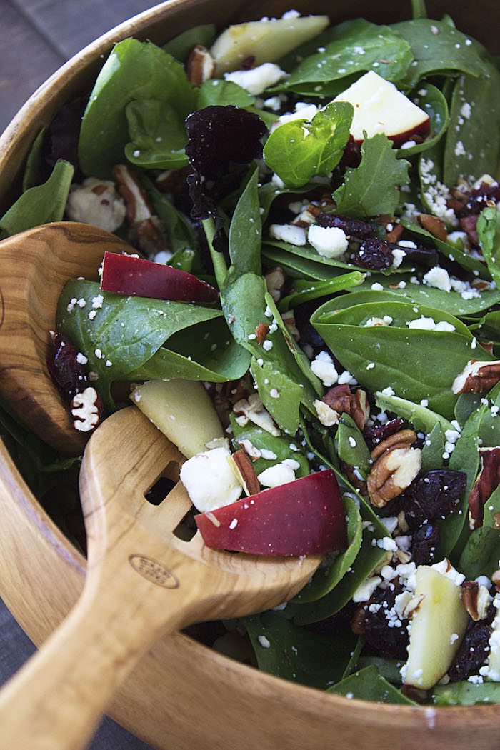 Apple Cranberry Feta Pecan Salad in a bowl with salad spoons. Thanksgiving side dish.