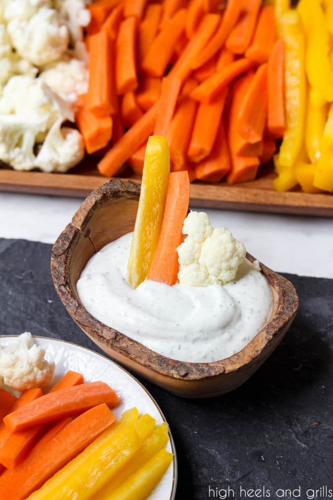 Yellow pepper, orange carrot, and white cauliflower sticking out of a bowl of dip to look like a Candy Corn Halloween Veggie Tray