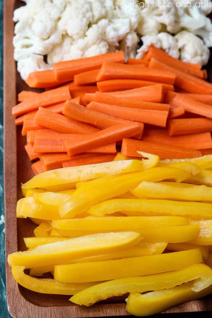 Candy Corn Halloween Veggie Tray with yellow peppers in the foreground, orange carrots in the middle, and white cauliflower in the background.