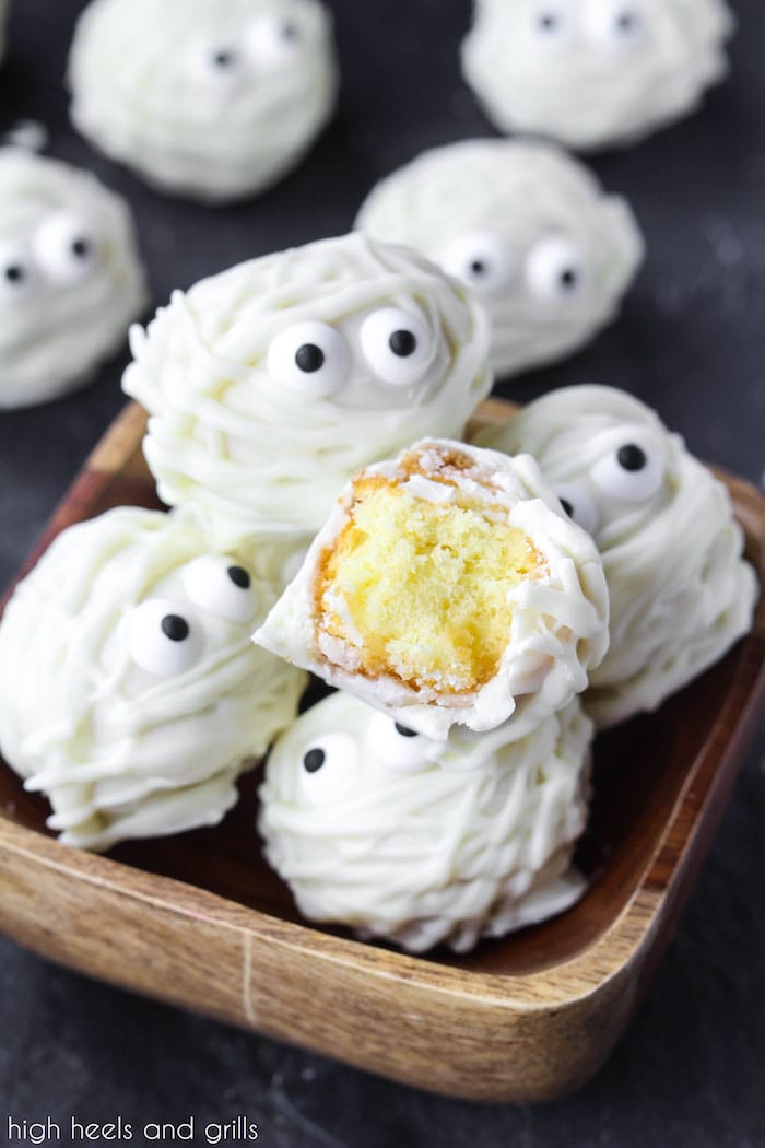 Small bowl of Easy Halloween Treat Donut Hole Mummies with one cut in half, showing the donut hole inside.