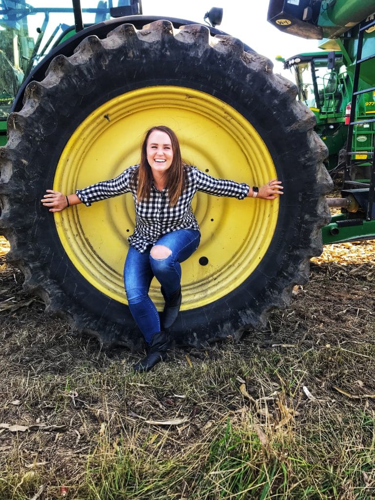 Sarah Averett in a tractor wheel on a corn farm in Iowa.