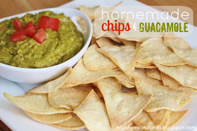 Plate of homemade tortilla chips with a bowl of homemade guacamole in the background and tomatoes on top of the guac.